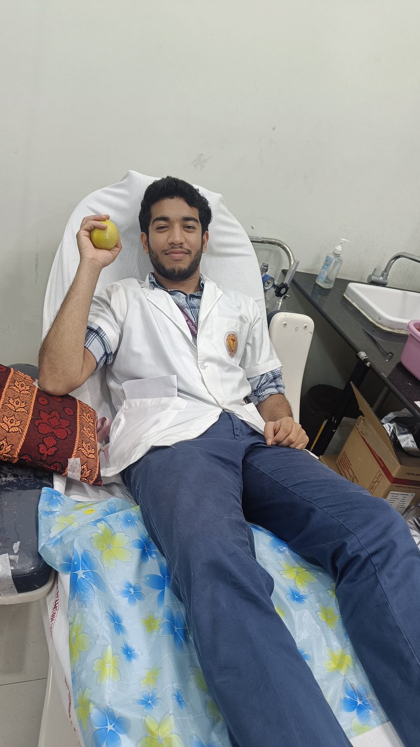 Sumit donating blood in a white coat at the donation drive.